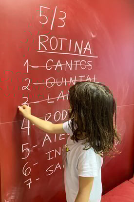 Criança em processo de alfabetização escrevendo na lousa.<br />
