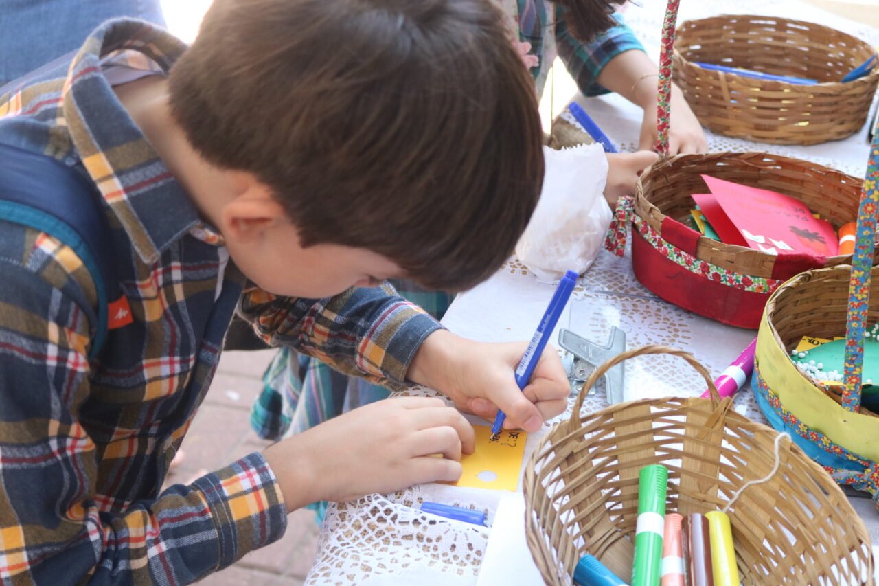 Menino preenchendo correio elegante na festa junina da escola viva